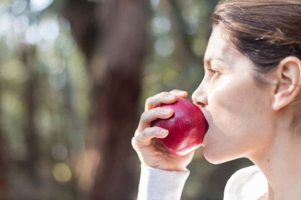 Close up of a woman eating an apple in a park